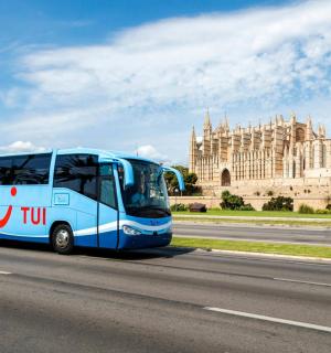 一辆蓝色巴士沿着一栋建筑物前的路行驶