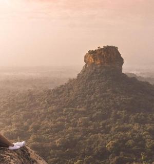 a woman sitting on the edge of a mountain