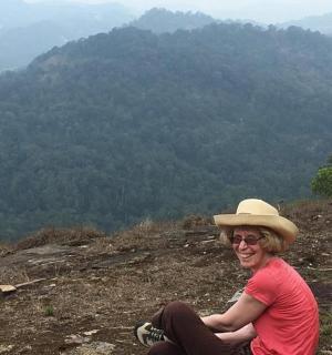 žena v klobouku sedící na vrcholu kopce