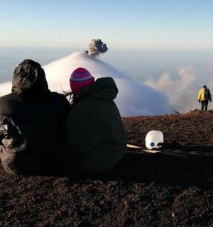 两个人坐在山上看着火山
