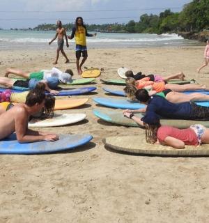 skupina lidí ležících na surfových prknech na pláži