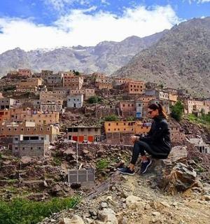 muž sedící na kopci a dívající se na vesnici