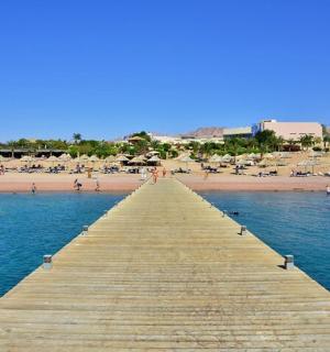 a wooden pier leading to a beach with chairs