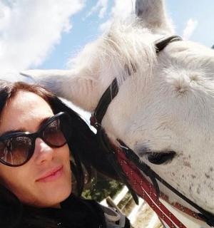 一名女子站在一匹白马旁边