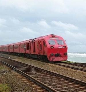 一列红色火车沿着海边的铁轨行驶