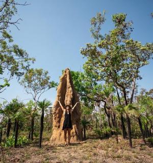 a woman is standing in front of a large tree stump