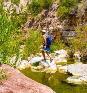 vyras eina per uolas upėje