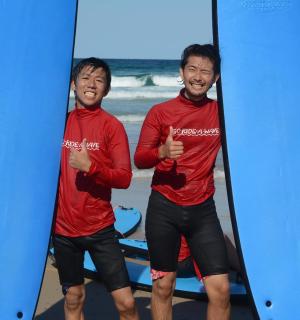 two men are holding their surfboards on the beach