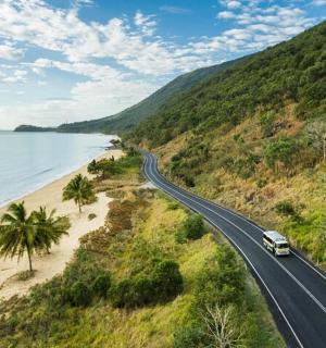 a truck driving down a road next to a beach