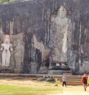 a group of people walking in front of a large rock wall