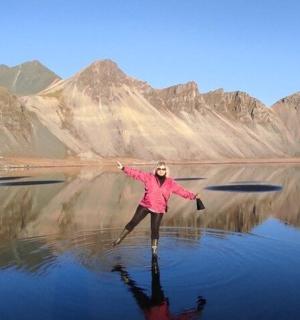 a woman standing in the water in front of mountains