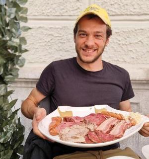 muž sedící na židli a držící talíř s jídlem