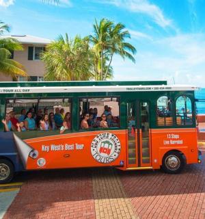 an orange bus filled with people on a street