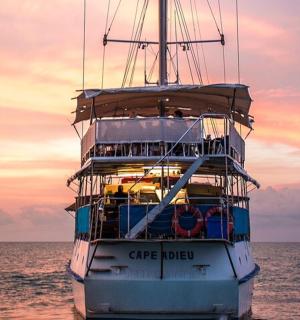 a large boat in the ocean with a sunset in the background