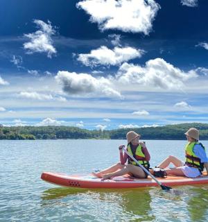 三个人坐在水中的桨板上