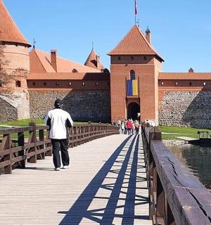 a man walking across a bridge in front of a castle