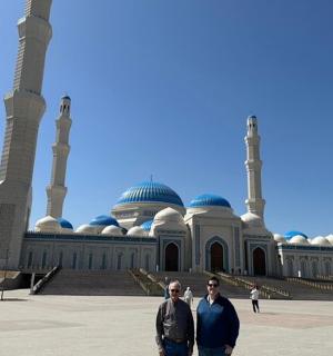 two men are standing in front of a mosque