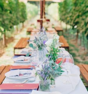 dlouhý stůl s talíři, sklenicemi a květinami