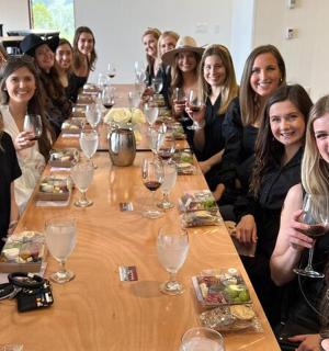 a group of women sitting around a table with wine glasses