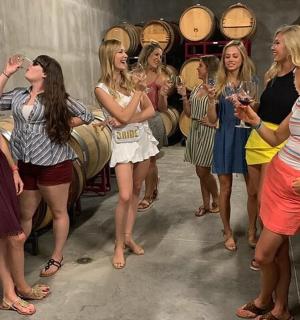 a group of women standing in a wine cellar holding wine glasses