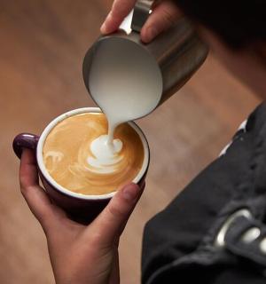 a person is pouring milk into a cup of coffee