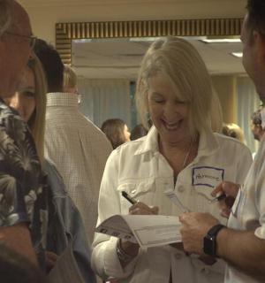 a woman is laughing while writing in a paper