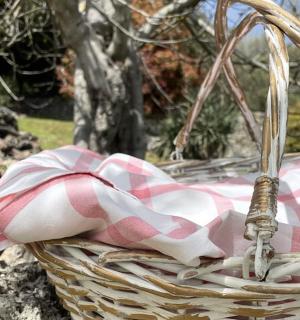 a wicker basket with a pink and white checkered towel