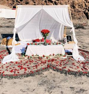 un llit amb flors i un dosser blanc a la platja