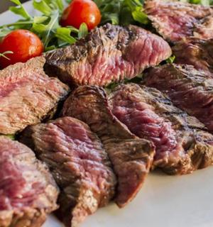 a plate of meat with a salad and tomatoes