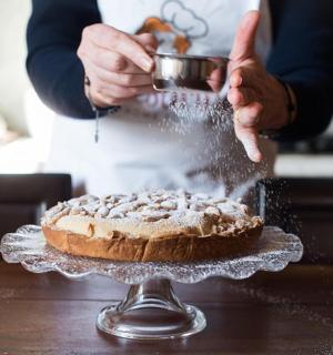 a person sprinkling powdered sugar on top of a pie