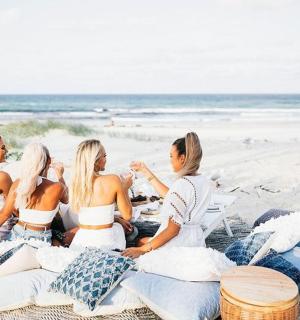 three girls sitting on a blanket on the beach