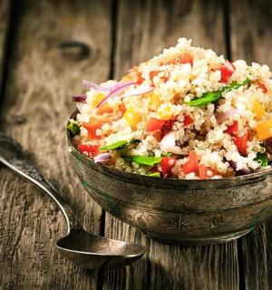 a bowl of rice and vegetables on a wooden table