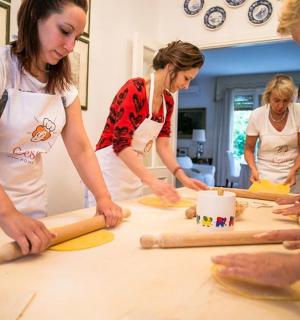 a group of people standing around a table making dough