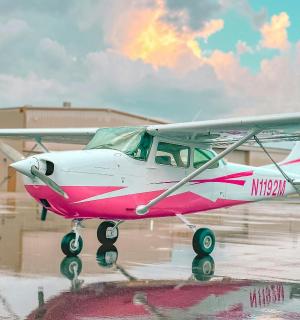 一架粉色和白色的飞机停在跑道上