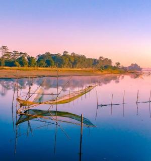 a boat sitting in the water at sunset