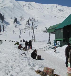 eine Gruppe von Menschen sitzt im Schnee auf einer Skipiste