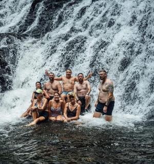 a group of people posing in front of a waterfall