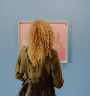 a woman with long curly hair standing in front of a painting