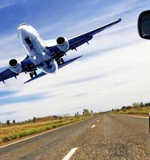 a plane is flying over a road with a car