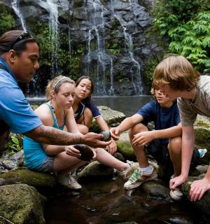 skupina lidí sedících na skalách v potoce