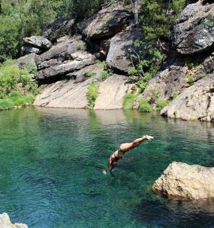 vyras, plaukiojantis upėje kalnuose