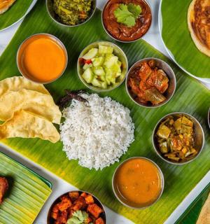 a table with plates of food on a banana leaf