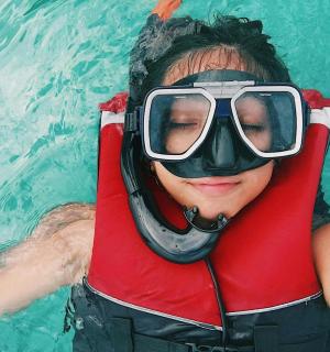 一名女子在泳池里戴着呼吸管和护目镜