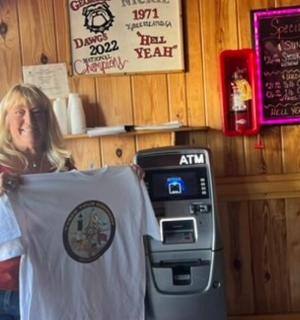a woman standing in a restaurant holding up a tshirt