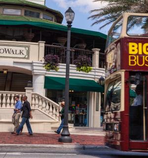 dvoupatrový autobus jedoucí po ulici s chodícími lidmi