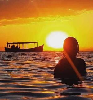 a person sitting in the water watching the sunset