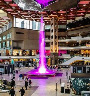 a large shopping mall with a purple fountain in the middle