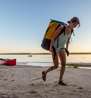 一名女子背着背包在沙滩上行走