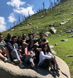 skupina lidí sedících na skále na kopci