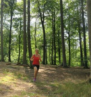 žena běžící lesnatou oblastí